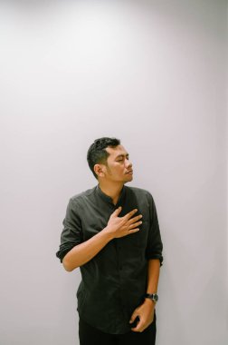 Eli göğsünde, samimiyetini ya da duygularını ifade eden genç bir adam..