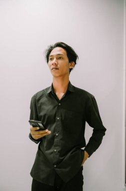 Genç bir adam akıllı telefonunu tutuyor, bağlanmaya ve iletişim kurmaya hazır..