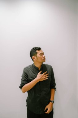 Eli göğsünde, samimiyetini ya da duygularını ifade eden genç bir adam..