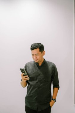 Genç bir adam akıllı telefonuyla haber okuyor, sürekli bilgilendiriliyor..