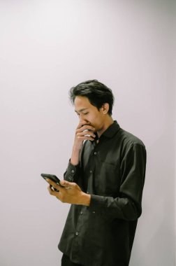 Genç bir adam akıllı telefonuyla haber okuyor, sürekli bilgilendiriliyor..