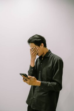 Genç bir adam akıllı telefonuyla haber okuyor, sürekli bilgilendiriliyor..