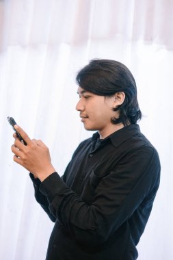 Genç bir adam akıllı telefonunu kullanır, muhtemelen bakınır ya da mesaj atar..