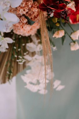 Orkideler ve ortancalar da dahil olmak üzere çeşitli çiçeklerin sergilendiği bir çiçek aranjmanının yakın çekimi. Kompozisyonda zarif doku unsurları, düğünler, etkinlikler veya botanik temalı arzular için mükemmel ve zarif bir estetik oluşturur.