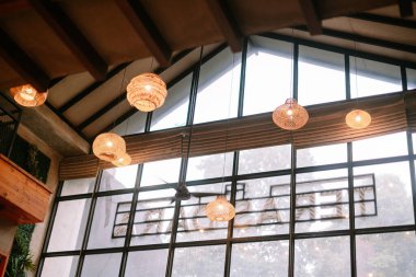 Tavandan zarif bir şekilde sarkan büyüleyici bir iç çekim, şık örülmüş kolye ışıkları. Geniş bir pencere, dış görünüşü çerçeveleyerek yeterli miktarda doğal ışık sağlar. Ayarlar, sıcak ışıklandırmayla çağdaş bir tasarım hissi uyandırıyor.