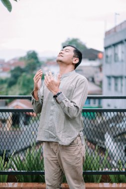 Bir binanın çatısında dua ve tefekkür eden, inanç, maneviyat ve bağlılığı somutlaştıran bir adamın huzurlu bir portresi. Şehir manzarasının arka planında ilahi güçle barışçıl bir bağlantı buluyor. Bir saygı duygusunu çağrıştırıyor ve...