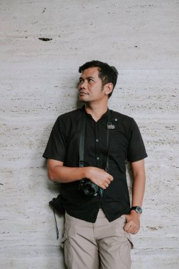 Klasik bir kamera tutan düşünceli bir fotoğrafçı, dalgın dalgın dalgın dalgın kaybolmuş. Bu resim, rahat bir şekilde giyinmiş bir adamı bir sonraki fotoğraf çalışmasını düşünürken gösteriyor. Arkaplan, çeşitli yaratıcı yapılar için uygun bir karşıtlık sunuyor 