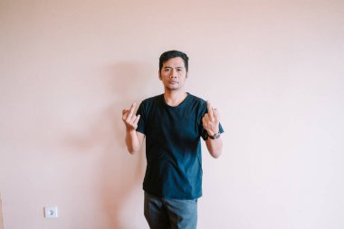 Tarafsız bir arkaplana karşı orta parmaklarını kaldırarak onaylamayan bir adam. Şiddetli duygular ve adaletsizliğe karşı tepkiler iletmek için muhalif ve başkaldırı sergiliyor..