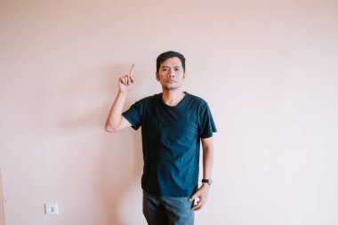 Sıradan bir şekilde giyinmiş bir adam arka planda dikiliyor. Yukarıdaki boşluğa metin, bilgi ya da tasarım eklemek için uygun. Bir fikri, yönü, tavsiyeyi ya da öneriyi temsil edebilir.