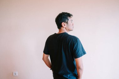 Siyah tişört giyen bir adam arkasını izleyiciye dönük durur, düşünceli bir ifadeyle başka yere bakar. Sakin bir iç mekan ortamında derin derin düşünüyor. Basitlik ve içgözlem tasvir ediyor.