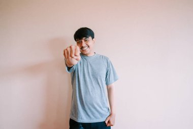 Neşeli genç bir adam kendinden emin bir gülümsemeyle ileri doğru yumruk atıyor. Kararlılık, başarı ve pozitif enerji hissini iletir. Güçlenmeyi, motivasyonu veya başarıyı resmetmek için mükemmel.