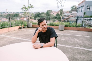 Genç bir Asyalı adam çatıdaki terasta bir masada oturup manzarayı seyrediyor. Düşünceli ve rahat görünüyor, şehir ortamında sakin bir düşünce anının tadını çıkarıyor. Sahne huzuru uyandırır ve koşuşturmadan kaçar. 