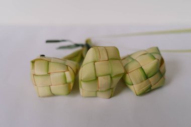 Üç adet ketuplu pirinç köftesi düz beyaz arka planda sergilenir. Bu geleneksel Malezya yemekleri genellikle şenlikli kutlamalarda sevilir. Her hamur işi dikkatlice dokunmuş palmiye yapraklarından yapılır, bir elmas ya da s şeklinde.