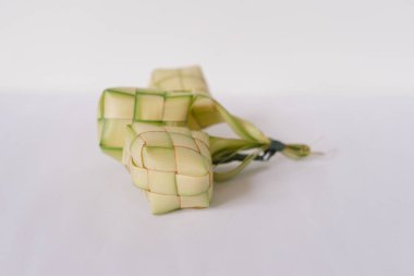 Ketupata yakın plan, beyaz arka planda örülmüş palmiye yapraklarından yapılan geleneksel pirinç köftesi. Bu yemek Kurban Bayramı ve Güneydoğu Asya 'daki diğer şenlikli etkinliklerde popülerdir..