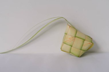 Geleneksel bir Endonezya ve Malezya yemeği olan ketçap kaplamasının yakından çekimi, örülmüş palmiye yapraklarından yapılır. Bu karmaşık kaplama tipik olarak pirinçle doldurulur ve pişirilir, özellikle Kurban Bayramı ve Ramazan ayında. Bir W üzerinde izole.