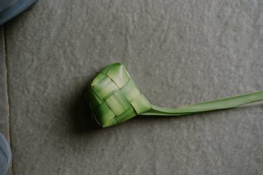 Geleneksel pirinç köftesi olan el yapımı ketupat, pişirilmeye hazırdır. Pirinçle dolu bu dokuma palmiye yaprağı kesesi, Endonezya ve Güneydoğu Asya 'daki Kurban Bayramı sırasında çok sevilen bir bayram yiyeceğidir. Karmaşık tasarımı ve doğal yeşil renk gösterisi