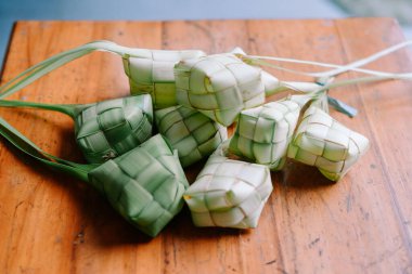 Geleneksel bir Endonezya pirinç keki olan ketupat, bayram kutlaması için lezzetlidir. Ahşap bir masada ele geçirildi. Kültürü, festival geleneklerini ve aşçılık sanatını temsil ediyor..