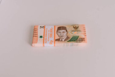 Temiz ve parlak bir yüzeye düzgünce istiflenmiş Endonezya Rupiah banknotları. Finans, ekonomi ve Endonezya para birimi kavramını gösterir.