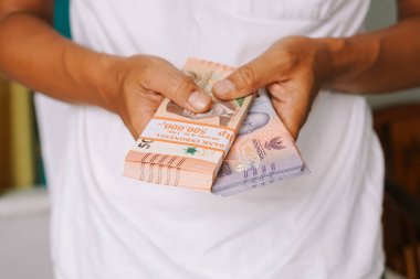 Bir kişi Endonezya Rupiah para destelerini elinde tutuyor, zenginlik, finansal güvenlik ve yatırım sergiliyor. Bankacılık, ekonomi ve para kazanma ve tasarruf kavramını gözler önüne serer..
