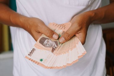 Endonezya Rupiah banknotları tutan bir adama yakın çekim. Ekonomik yatırım ve mali işlemleri gösteriyor. Tasarruf ve parasal refaha odaklan