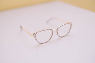 İnce altın çerçeveli zarif gözlükler, gösterişli stil ve görüş bakımı. Moda, sağlık ve yaşam tarzı projeleri için mükemmel. Bu resim gözlüklerin detaylarına ve zarif tasarımına odaklanır..