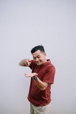 Hevesli bir adam hayali bir ürün sunuyor, eliyle işaret ediyor, beyaz arka planda izole edilmiş.