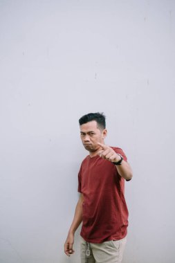 Sert Asyalı adam kızgın bir ifadeyle kamerayı işaret ediyor. Ciddi bakışlarına odaklan..