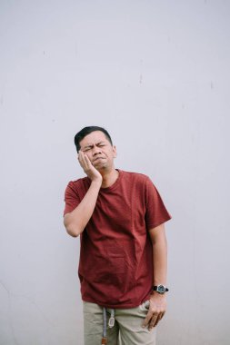 Korkunç bir diş ağrısından muzdarip bir adam, yanağını düz bir duvara dayayıp acı çekiyor.