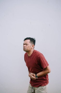 Asyalı bir adam mide ağrısından, sindirim sorunlarının belirtilerini ve olası hastalıklardan dolayı rahatsızlığını gösterir.. 