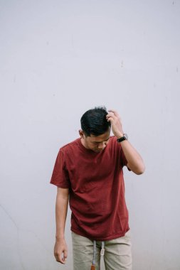 Kestane rengi gömlekli bir adam. Tarafsız bir arka plana kafa yoruyor. Düşüncelere dalmış.