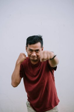 Boks pozisyonunda kararlı bir adam, her türlü meydan okumaya hazır. Odaklanmış bakışlarıyla kendine güveni ve gücü ifade ediyor..