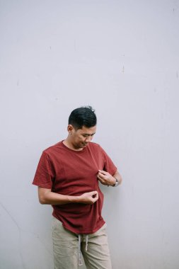 Adam bordo tişört kumaşını inceliyor. Kopyalama alanı olan minimalist bir arkaplan. Özgünlük ve günlük giysiler. 