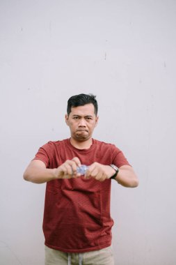 Bir adam boş bir plastik şişeyi eziyor, geri dönüşümü desteklemek için kararlı bir ifade sergiliyor.