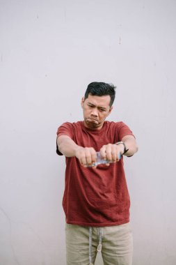 Stresli bir yüz ifadesi gösterirken plastik su şişesini açmaya çalışan sinirli bir adam. Açık hava çekimi..