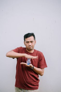 Asyalı adam elinde plastik bir şişeyle plastik geri dönüşüm kampanyası düzenliyor. Daha yeşil bir gelecek için sürdürülebilirlik ve çevre dostu uygulamalara odaklanın.