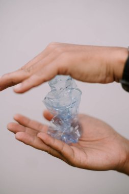 Elinde ezilmiş bir plastik şişe tutan kişi, çevresel koruma için geri dönüşüm ve atık azaltımını vurguluyor