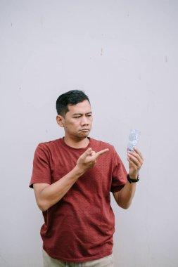 Parçalanmış plastik şişeyi işaret eden bir adam çevresel kaygılarını iletiyor ve sürdürülebilir bir yaşam tarzında geri dönüşüm çabalarına ihtiyaç duyuyor.