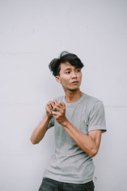 Düşünceli, sıradan giyinmiş genç bir adam, düşünceli bir duruşta düz bir duvara bakıyor ve başka tarafa bakıyor.. 