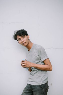 Genç adam mola veriyor, su şişesini beton duvara dayıyor. Sıcak bir günde susuz kalan erkek.