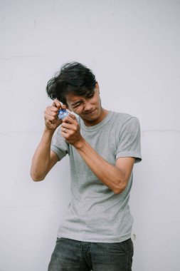 Hüsrana uğramış bir ifadesi olan genç adam, zor bir hap ambalajını açmaya çalışıyor..