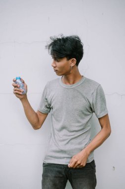 Genç bir adam elinde küçük bir plastik su şişesi tutuyor, geri dönüşüm, çevre ve sürdürülebilirlik sorunları üzerine kafa yoruyor.