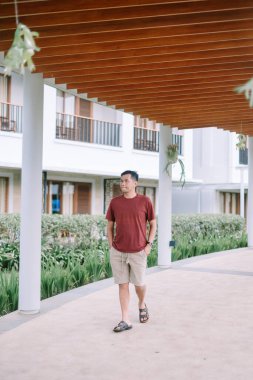 İnsanoğlu modern tepe örtüsünün altında sakin bir şekilde yürür. Öylesine giyinmiş, tropikal tatil köyünün atmosferinin tadını çıkarıyor.