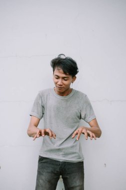 Genç adam görünmez bir piyanoyu kaygısız bir ifadeyle beyaz bir arkaplana karşı şakacı bir şekilde taklit ediyor.