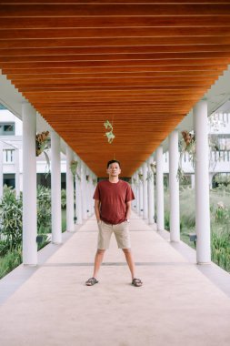 Simetrik çizgiler ve tropikal bitkilerle modern mimari geçitte duran adam. Tatilde bir turist