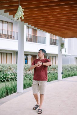 Adam, aydınlık bir günde modern bir tepe örtüsü altında saatlerini kontrol ediyor..