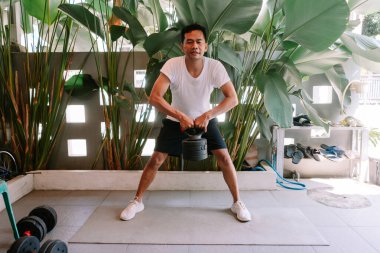 Spor salonunda kettlebell egzersizi yapan bir adam. Açık hava sporu, formda ve sağlıklı bir yaşam tarzı..