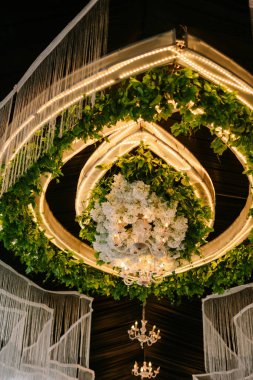 Özel etkinlik dekorasyonu için çiçek avizesi ve hafif çelenklerle zarif bir iç mekan.