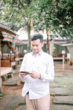 Açık havada akıllı telefon kullanan bir adam. Telefonundan bir şeyi kontrol ediyor..