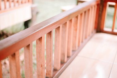 Ahşap bir balkon korkuluğuna yakın çekim. Açık kahverengi tonlu minimalist tasarım elementi. Görüntü huzuru ve doğayla bağlantıyı çağrıştırıyor..