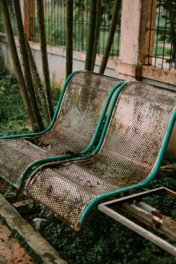 Giyinik metal park bankları, doğanın ortasında sakin bir yalnızlık hissi uyandırıyor. İnce çürüme görsel entrika ekler, dinlenme ve huzur dolu anların hikayelerini anlatır.